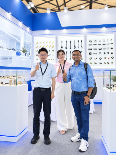 Three people at a connector exhibition booth with neutral signage.
