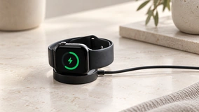 Black smartwatch on its charging cradle; application concept.