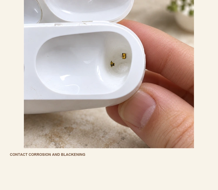 Corrosion and blackening on two charging contacts inside an earbud case.
