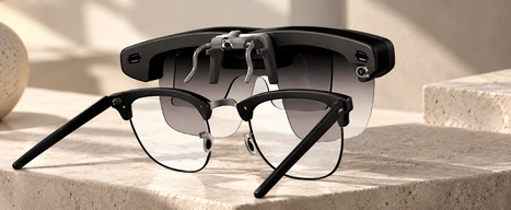 Smart glasses positioned behind a pair of optical glasses.